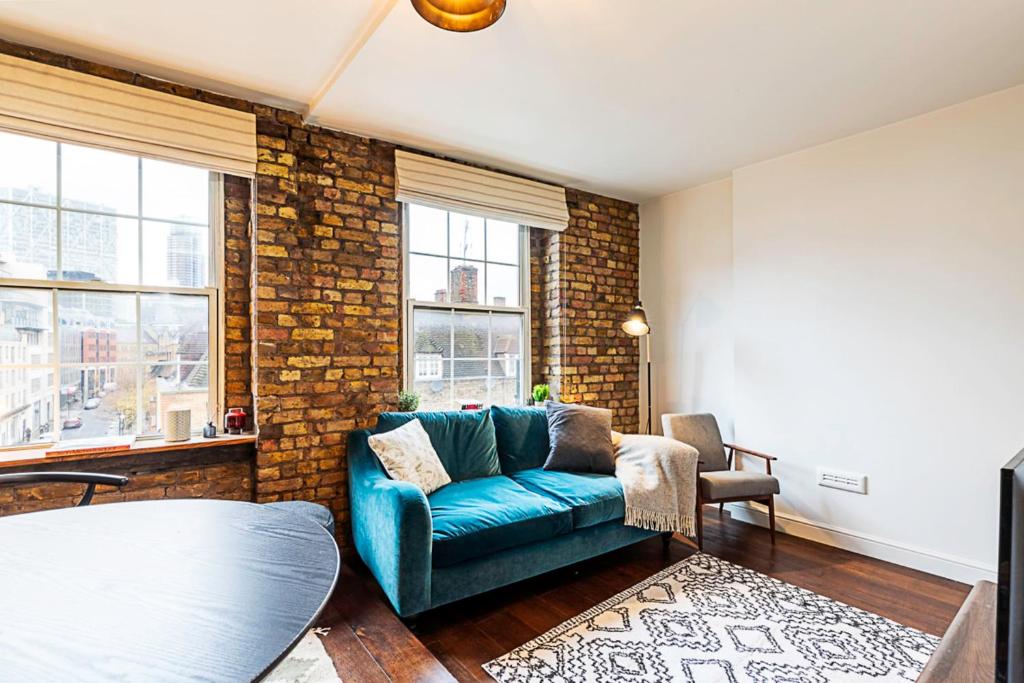 a living room with a blue couch and a brick wall at Charming Shoreditch Apartment in London