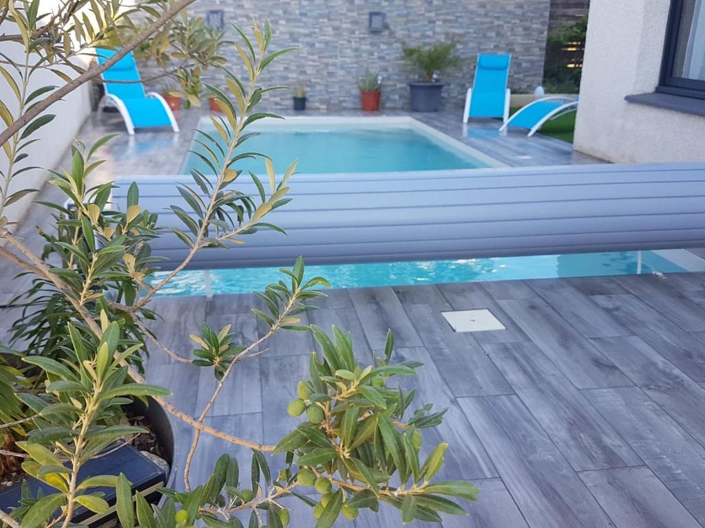 ein Pool mit zwei blauen Stühlen neben einem Haus in der Unterkunft Morena Villa Familiale in Bompas