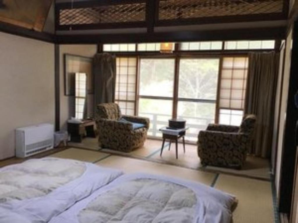 a bedroom with a bed and chairs and a large window at Sawa no Yado Kinsenkaku - Vacation STAY 45272v in Date