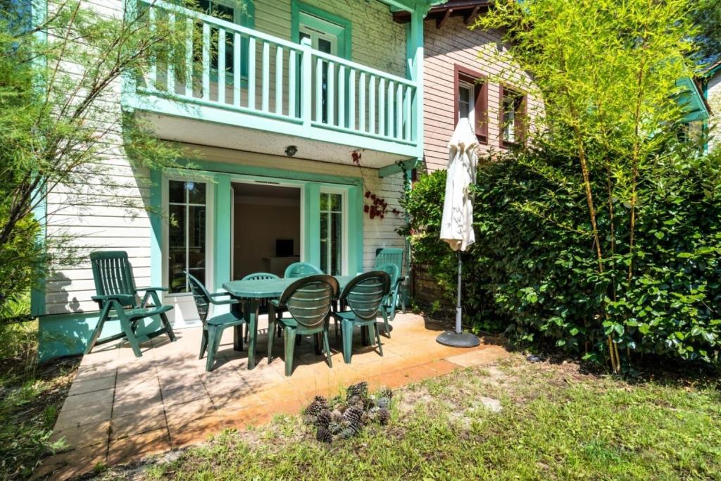 un patio avec une table et des chaises devant une maison dans l'établissement Les Maisons de Lacanau les Pins - maeva Home - Maison 3 Pièces 8 Personnes - Budget MAE-9364, à Lacanau