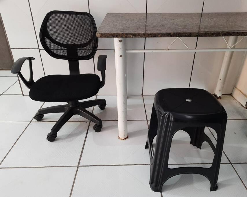 una silla negra sentada junto a una mesa con un taburete en Espaço perto da Unifesspa III, en Marabá