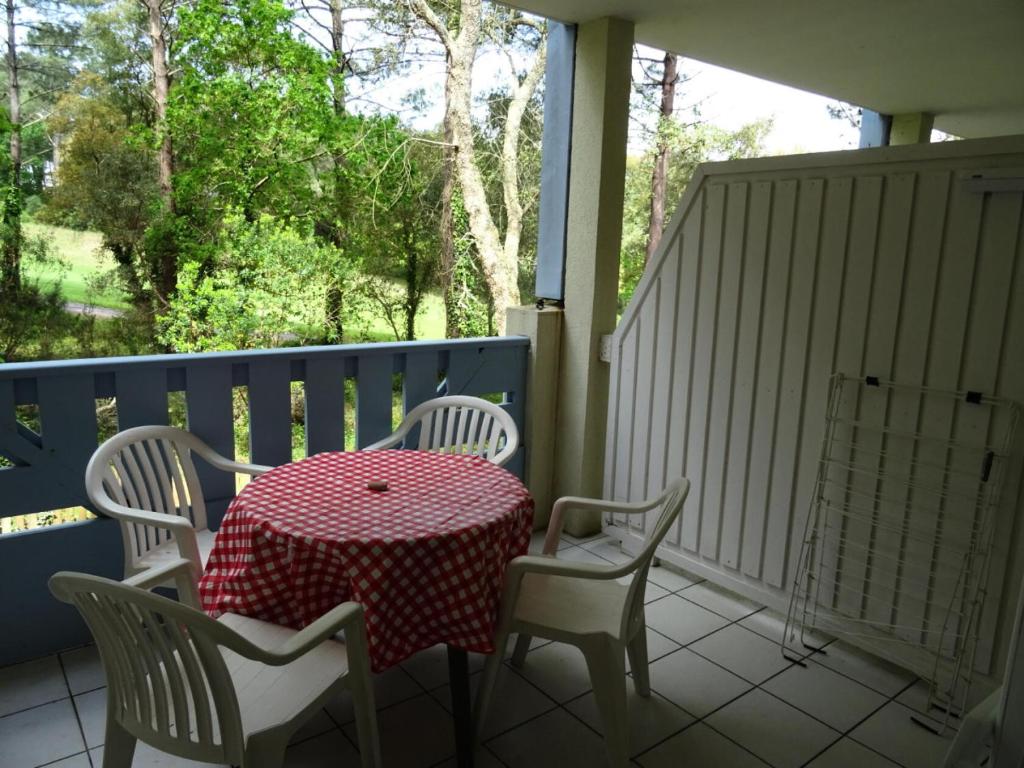 - une table et des chaises sur une terrasse couverte avec une nappe rouge et blanche dans l'établissement Village Moliets - maeva Home - Appartement 2 pièces 4 personnes - Confort MAE-3094, à Moliets-et-Maa