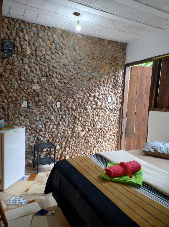 um quarto com uma cama com uma parede de pedra em Pesque e Sorte Escondidinho em Santana do Riacho