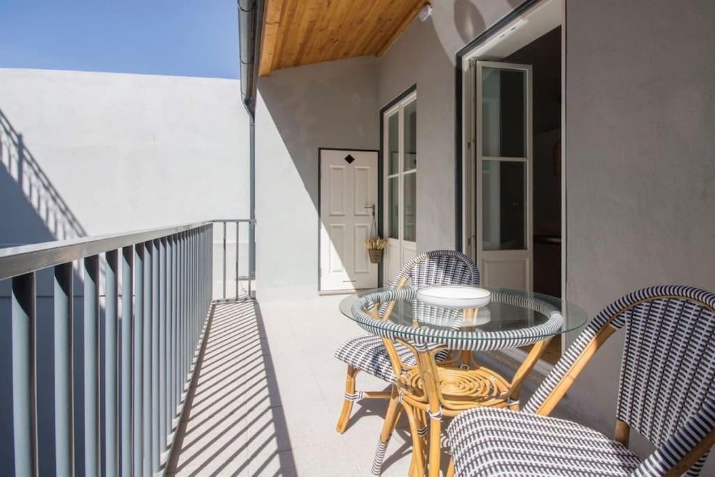 een patio met een glazen tafel en stoelen op een balkon bij 157 Flores Apartment in Porto