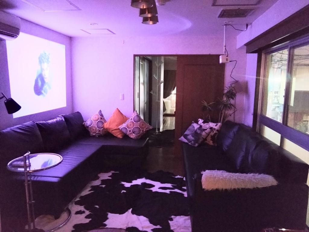 sala de estar con sofá negro y paredes moradas en Ito Building 1st floor B, 2nd floor, 3rd floor - Vacation STAY 50412v, en Tokio