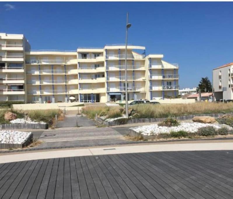 un grand immeuble blanc dans un parking dans l'établissement Studio 22m2 classé * calme et accès direct Plage, à Saint-Hilaire-de-Riez