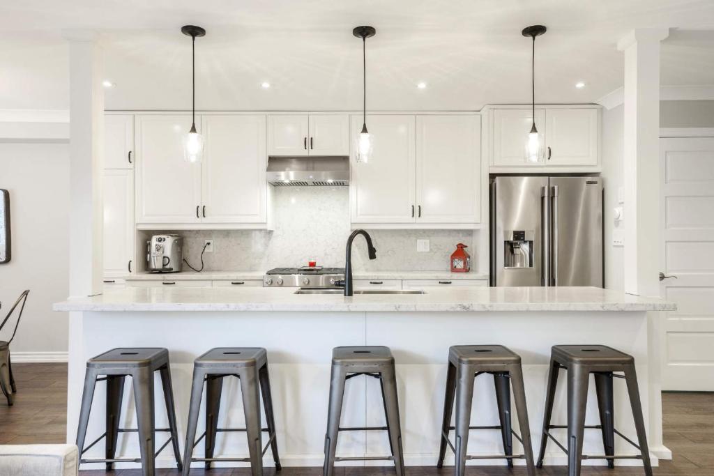 a kitchen with white cabinets and a counter with stools at Centrally Located Stylish House in Vaughan