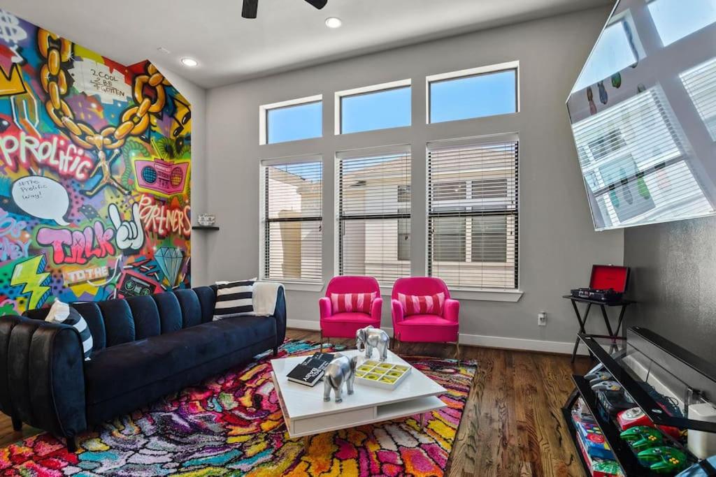 ein Wohnzimmer mit einem Sofa und 2 rosafarbenen Stühlen in der Unterkunft Prolific Theme Suite Ft Jacuzzi Tub 9Os Fun & Content Spaces in Houston