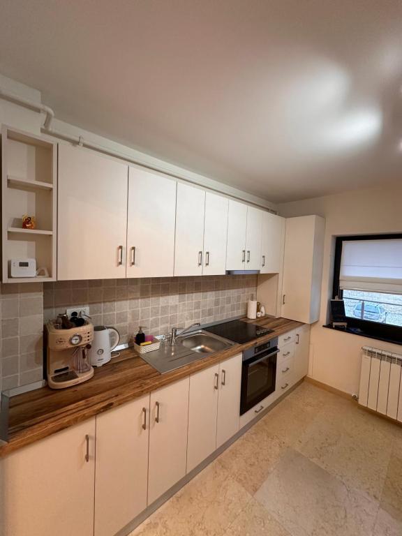 a kitchen with white cabinets and a sink at Mountain View Apartment in Piatra Neamţ