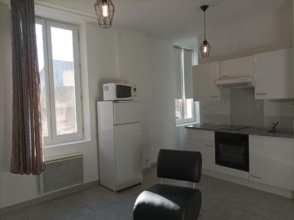 Il comprend une cuisine équipée d'une chaise et d'un réfrigérateur blanc. dans l'établissement 