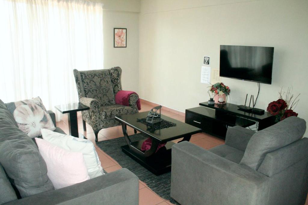 een woonkamer met 2 banken en een flatscreen-tv bij Libem Lodge 11 in Edenvale