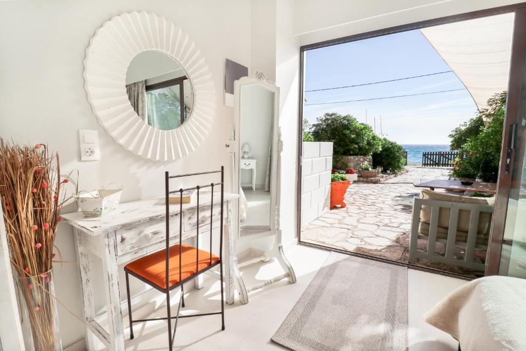 a bathroom with a mirror and a table with a chair at Louiza Apartments in Agios Gordios