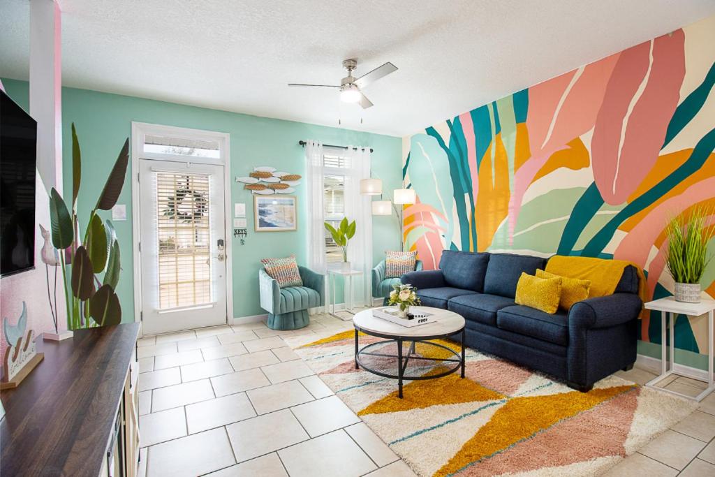 ein Wohnzimmer mit einem blauen Sofa und einer farbenfrohen Wand in der Unterkunft Luxury Beach Retreat Townhouse Sleeps 8 in Gulfport