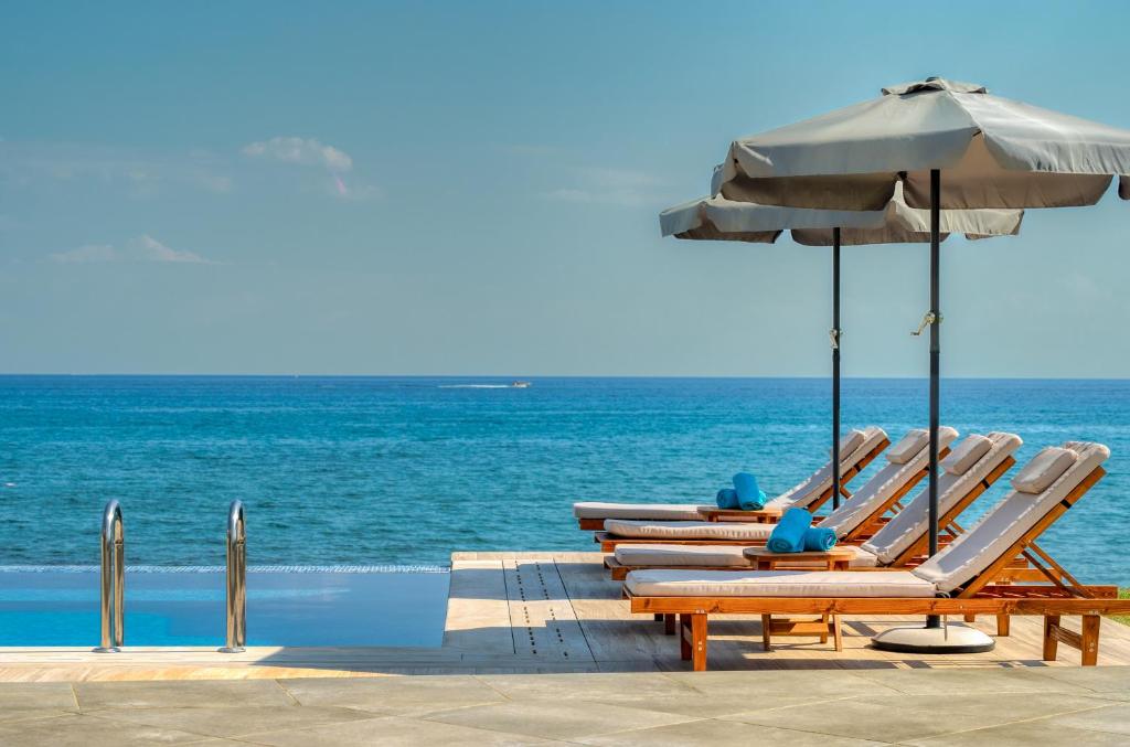 a group of chairs and an umbrella on the beach at Violet Beach Front Private Villa in Laganas