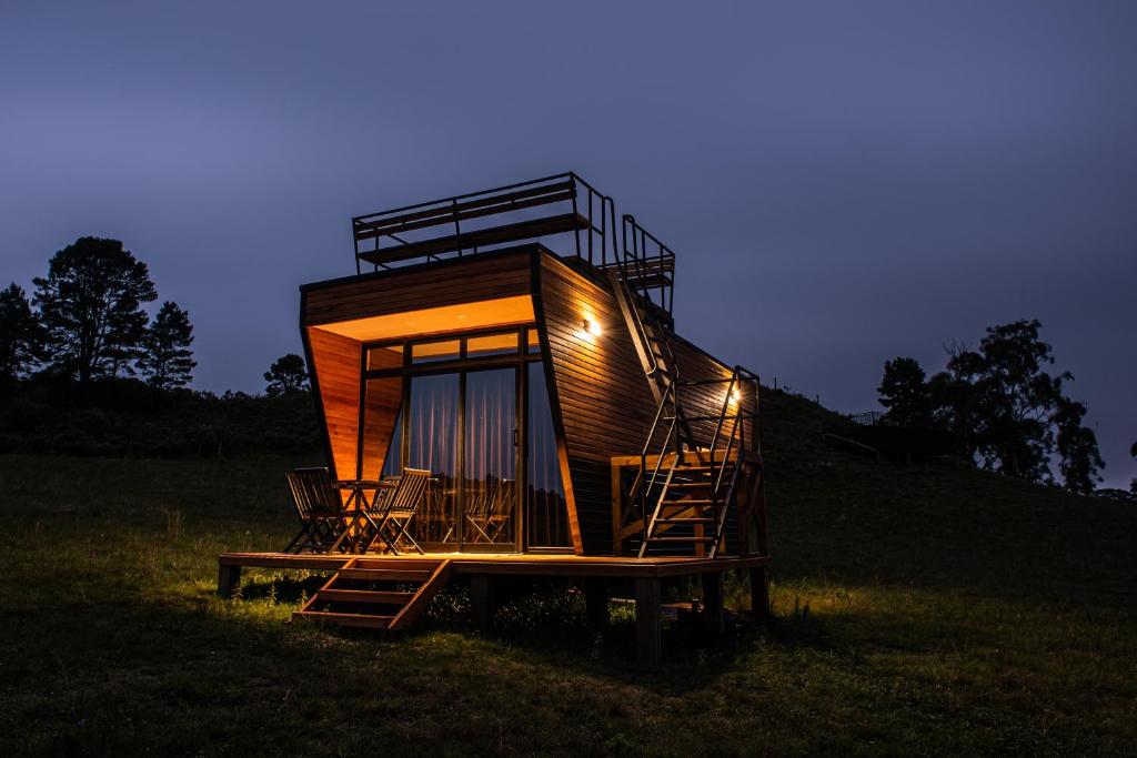 una casa del árbol sentada en un campo por la noche en Tiny House Purunã - Refúgio Inspirador en Balsa Nova