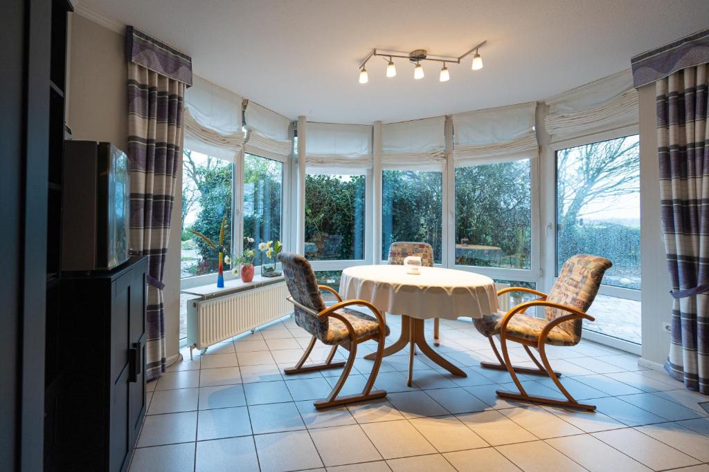 comedor con mesa, sillas y ventanas en Stellmann’s Gästehof, en Bruchhausen-Vilsen