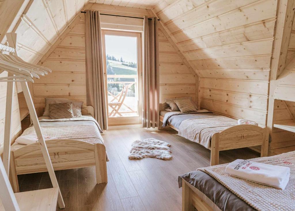 a bedroom with two bunk beds and a large window at Chałpy Pod Ostryszem in Ciche