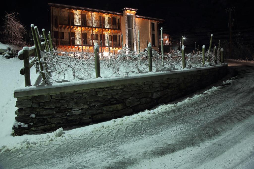 una recinzione in pietra nella neve di fronte a un edificio di Agriturismo Prada a Bianzone