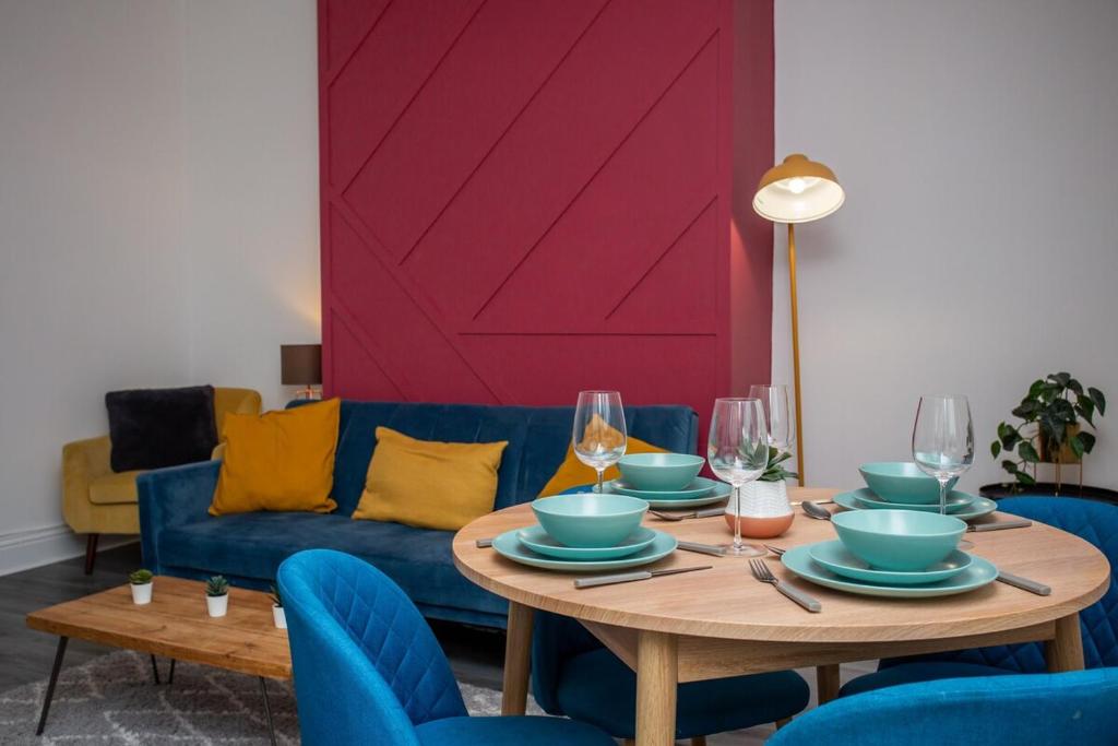 une salle à manger avec une table et un canapé bleu dans l'établissement The Ferndale - Spacious 3 Bed Apartment, à Pallion