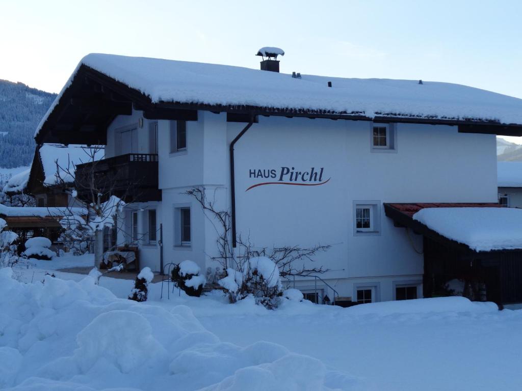 un edificio cubierto de nieve con un cartel. en Haus Pirchl, en Westendorf