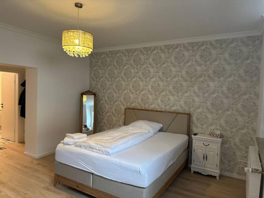 1 dormitorio con cama y lámpara de araña en Paris: Messe-/Business-/FeWo DUS, en Hilden