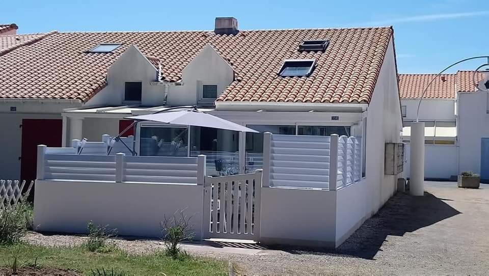 une maison blanche avec un portail et une clôture dans l'établissement Maison saisonnière de Mer, à Plage-des-Demoiselles