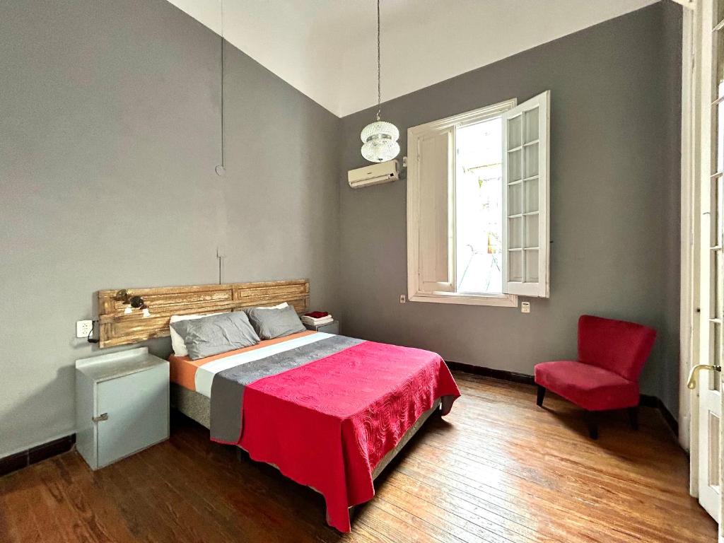 a bedroom with a bed and a red chair at Hostel Bohemian House in Montevideo