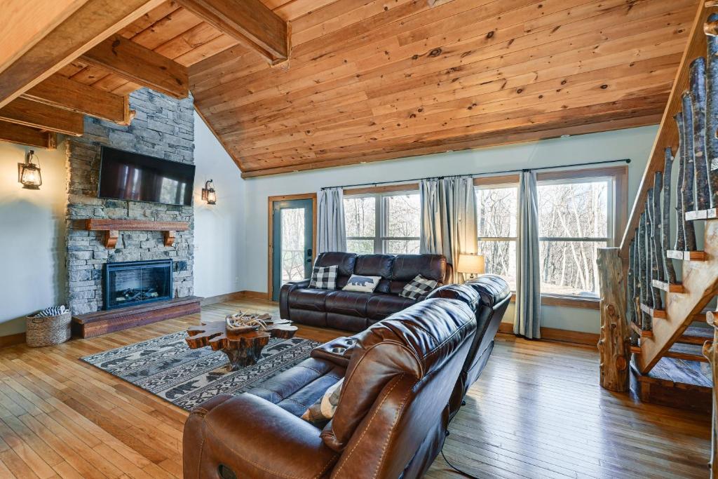 a living room with a leather couch and a fireplace at Bryson City Cabin Deck and Mountain-View Hot Tub in Nantahala