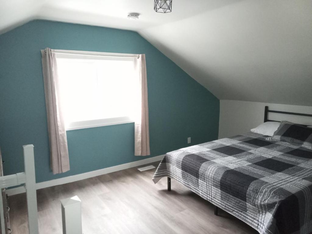 een slaapkamer met een bed en een raam bij Cozy Quincy in Bruce Mines