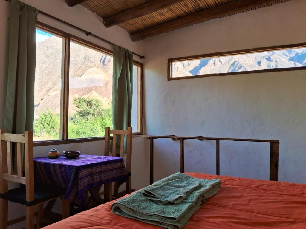 a bedroom with a bed and a table and windows at Cabañas APU in Maimará