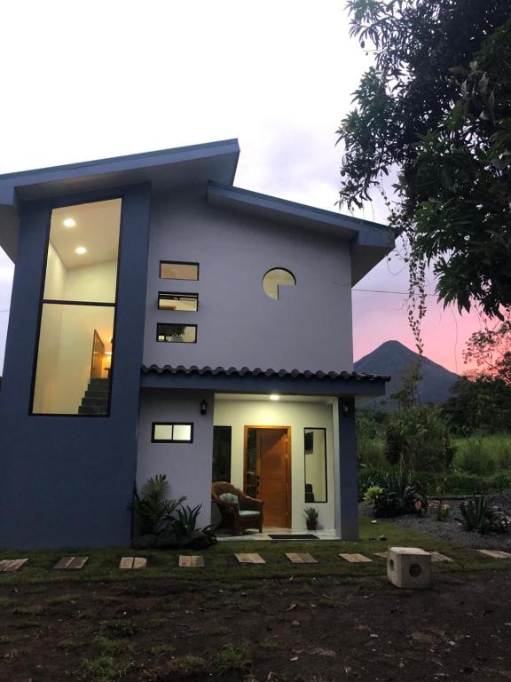 a blue and white house with the sunset in the background at Luxury Villas Arenal in Fortuna