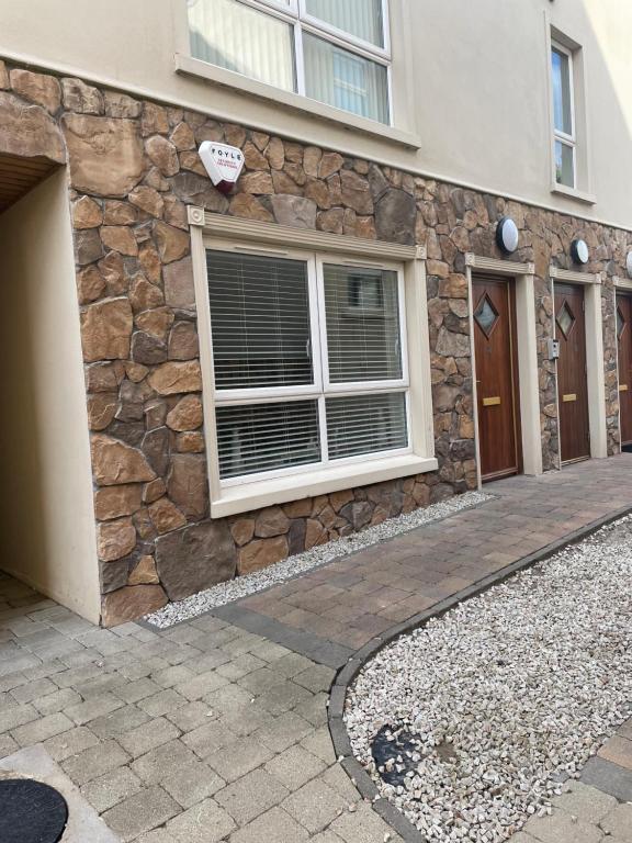 fachada de piedra de un edificio con ventana en Ballycastle, Beachside Apartment, en Ballycastle