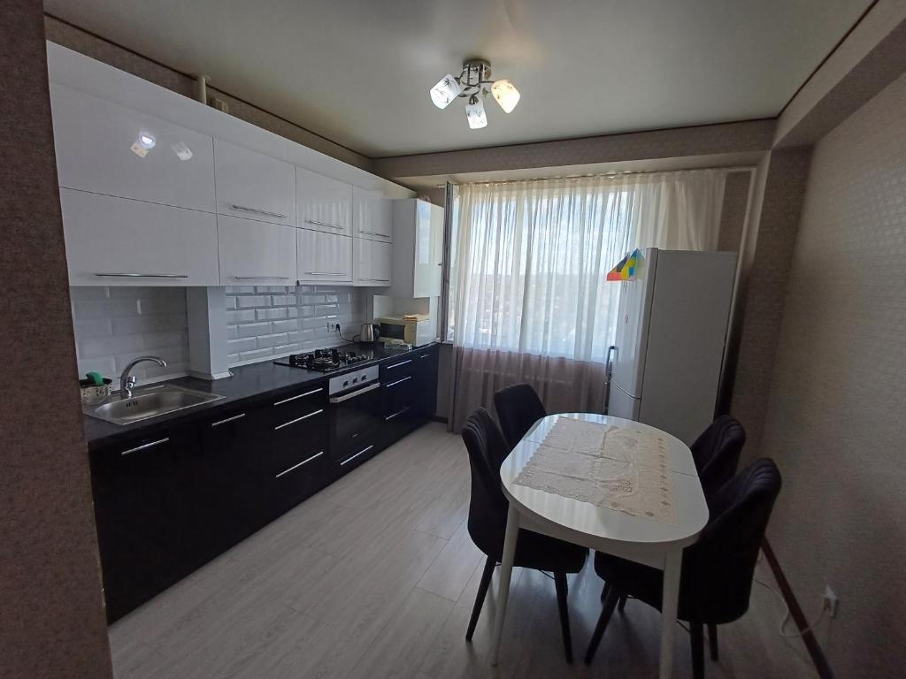 a kitchen with a table and chairs and a refrigerator at Apartament in Chişinău