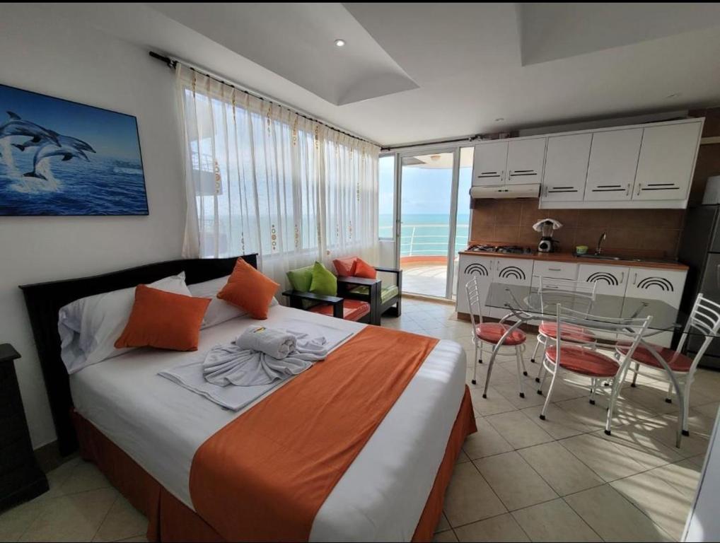 a bedroom with a bed and a table and a kitchen at Hotel Arco Iris in Atacames