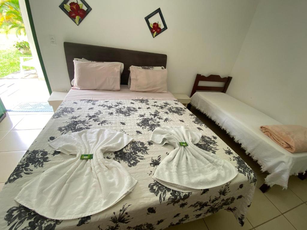 a bedroom with a bed with two dresses on it at Pousada Meu Cantinho in Conservatória