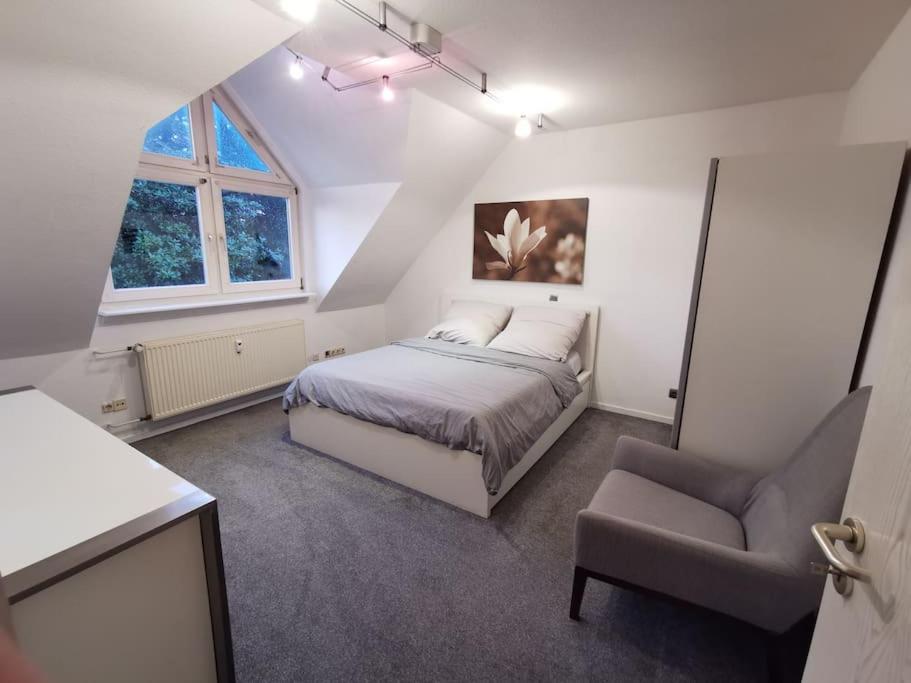 a bedroom with a bed and a chair at Helle Maisonnette Wohnung Penthouse in Recklinghausen