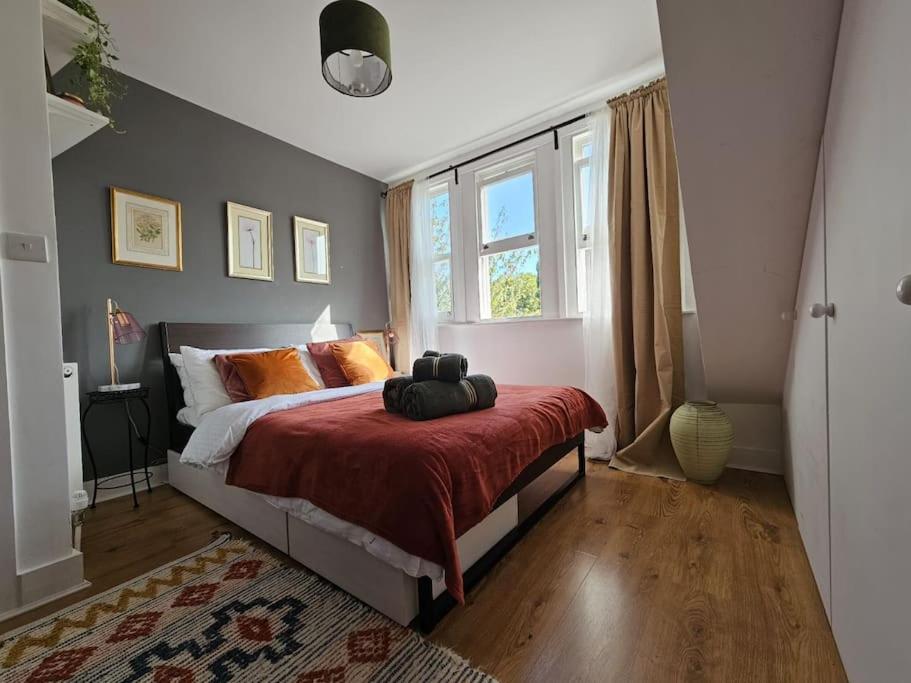a bedroom with a bed with orange pillows and a window at Cosy and quiet one bedroom Thames flat in London