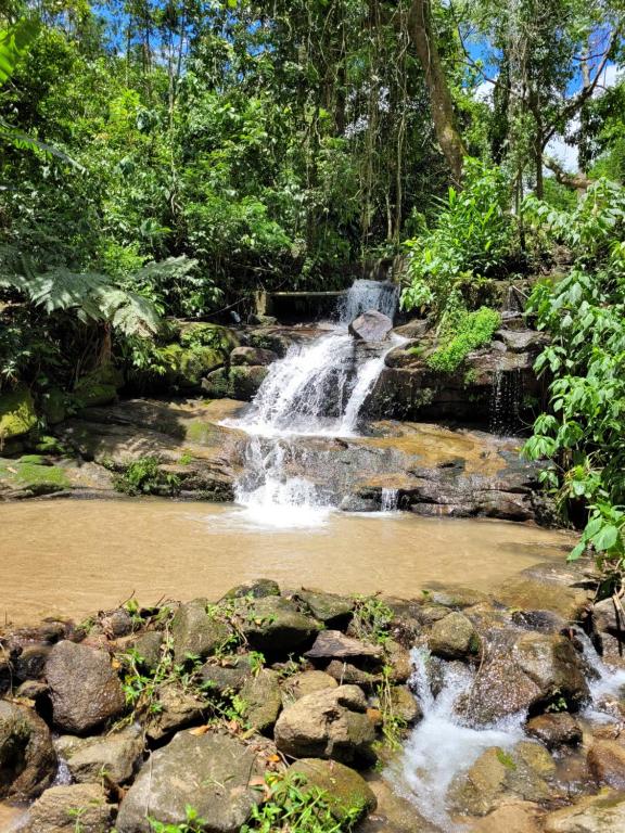 uma cascata no meio de um rio com pedras em Pousada Pedra Grande - SANA em Macaé
