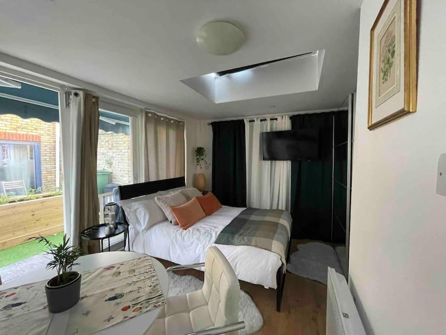 a bedroom with a bed and a table in a room at Cosy studio on the Thames in London