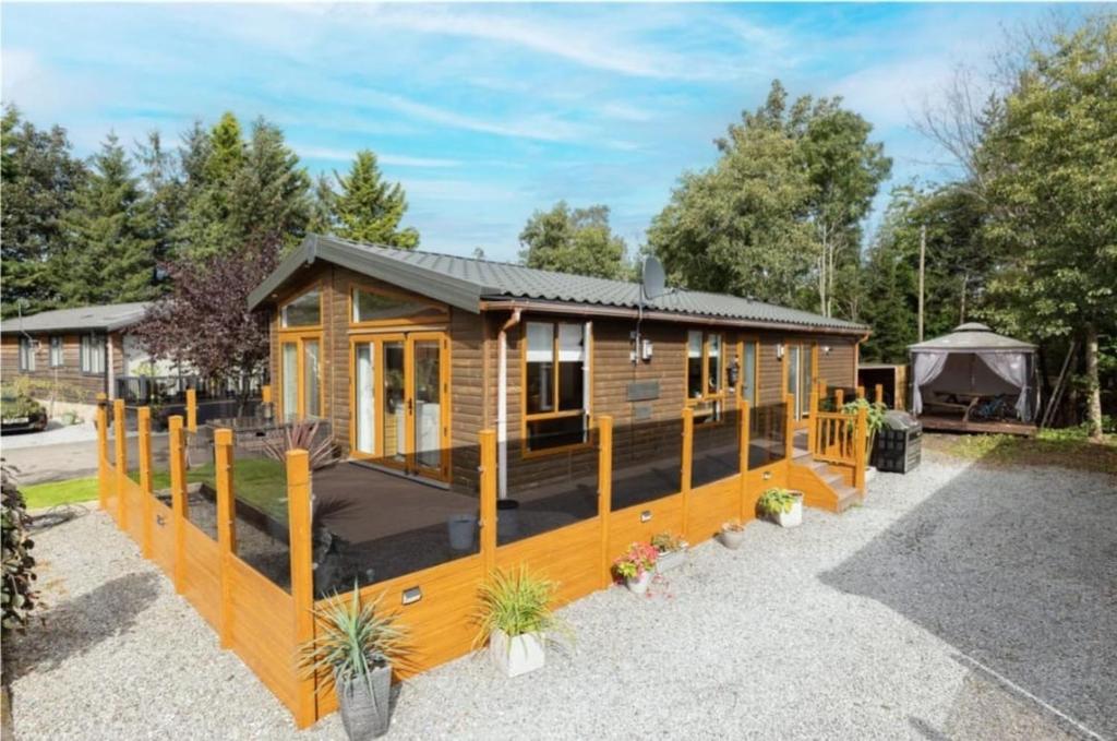 eine Blockhütte mit einer Terrasse und einem Pavillon in der Unterkunft Loubet Extra Large Lodge in Auchterarder