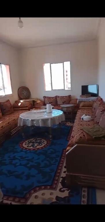 ein Wohnzimmer mit einem Tisch und einem blauen Teppich in der Unterkunft Samlalia home in Marrakesch