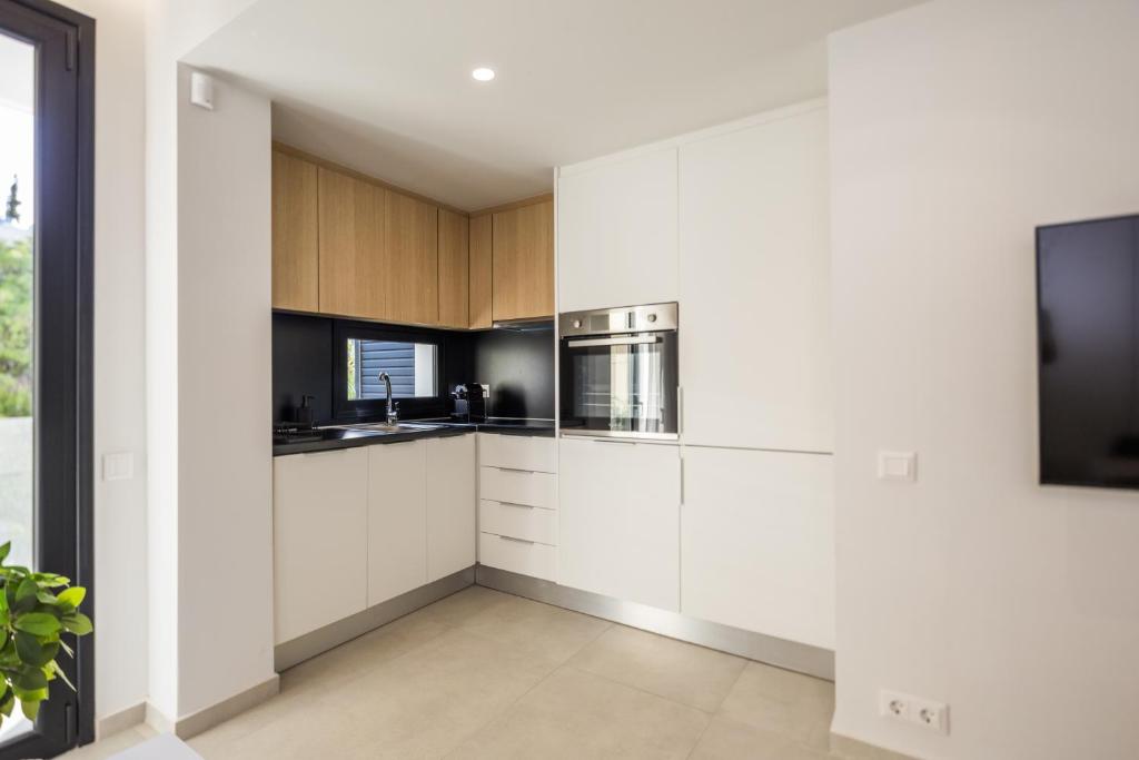 a kitchen with white cabinets and stainless steel appliances at Varkiza Luxury Suites by Raise in Vari