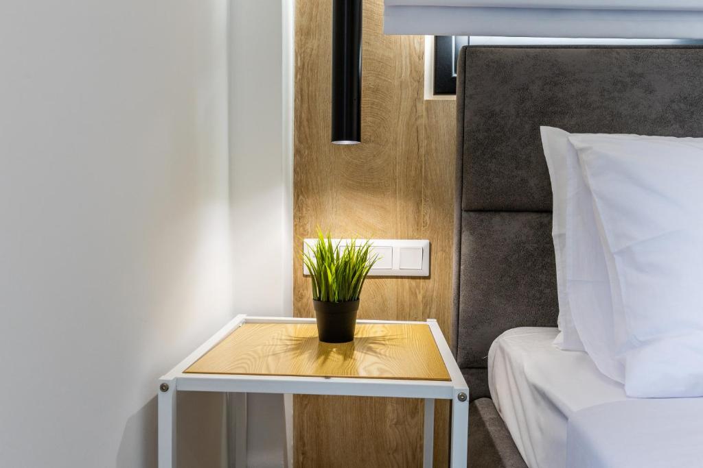 a small table with a plant on it next to a bed at Varkiza Luxury Suites by Raise in Vari
