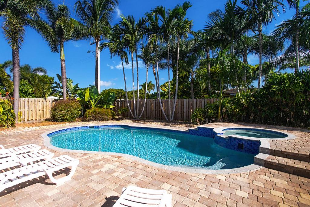 una piscina con 2 sillas blancas y palmeras en Deluxe 5BR Home in Dania Beach near Beach, Casino, Heated Pool, en Dania Beach