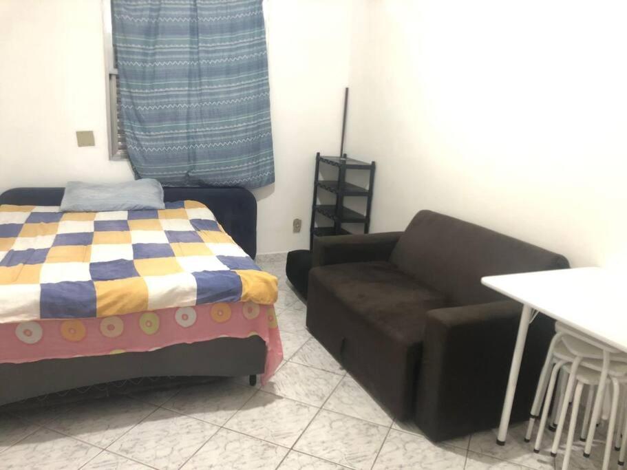 ein Wohnzimmer mit einem Sofa und einem Stuhl in der Unterkunft Kitnet para temporada 600 m Praia do Gonzaguinha in São Vicente
