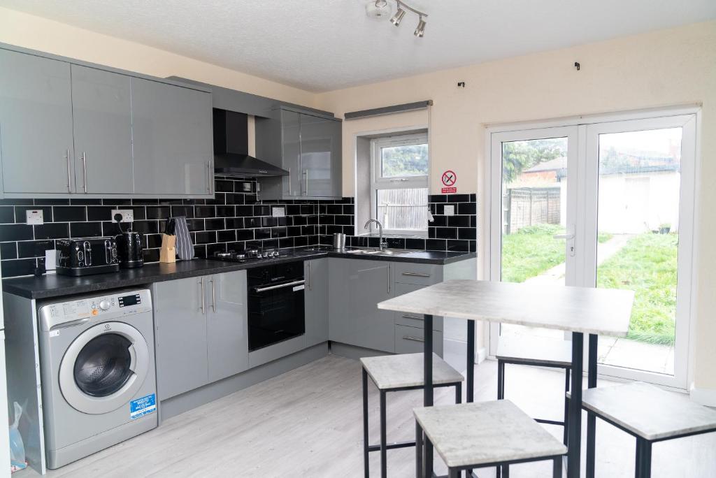 a kitchen with a washing machine and a table at Beautiful 5 single bedroom house in Dagenham