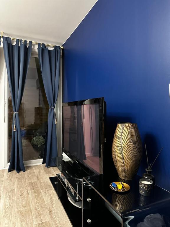 ein Wohnzimmer mit blauen Wänden und einem TV in der Unterkunft Proche stade de France avec parking in Saint-Denis