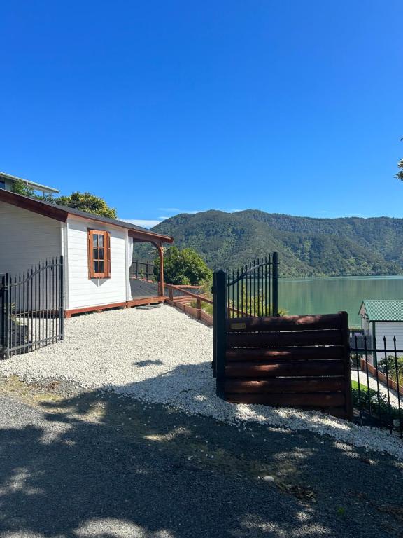 una recinzione accanto a una casa con un lago di The Petite Suite a Havelock