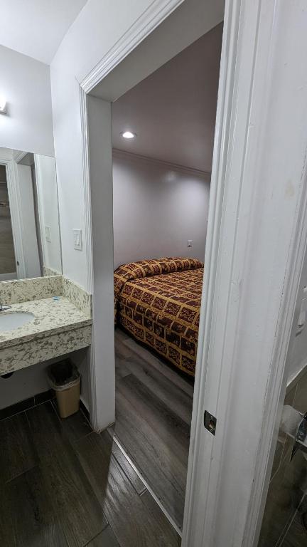 a bedroom with a bed and a sink and a mirror at Airport Motel - Inglewood in Inglewood