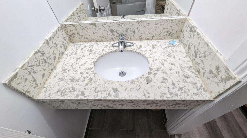 a bathroom sink with a marble counter top at Airport Motel - Inglewood in Inglewood